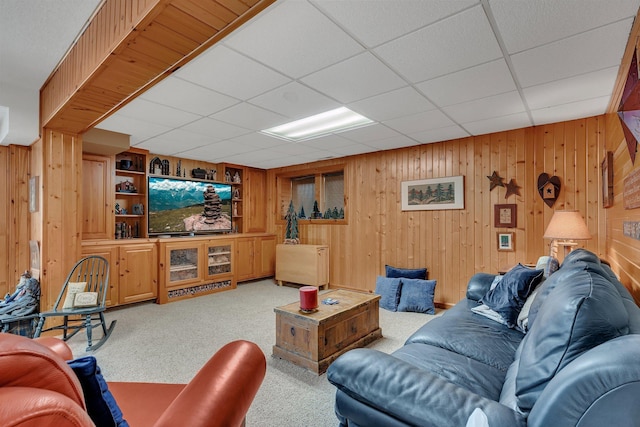 carpeted living area with wooden walls and a paneled ceiling