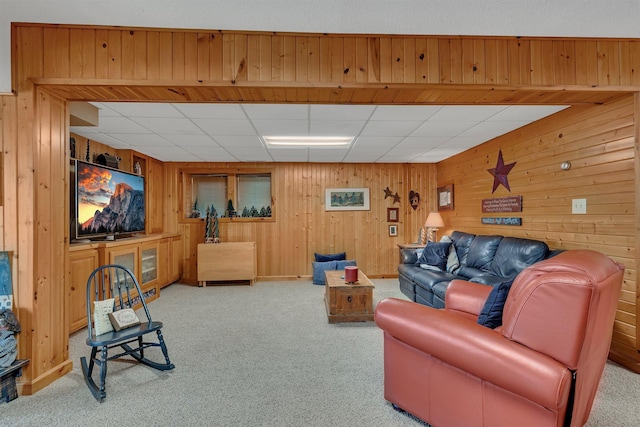 living area with wood walls, carpet flooring, and a paneled ceiling