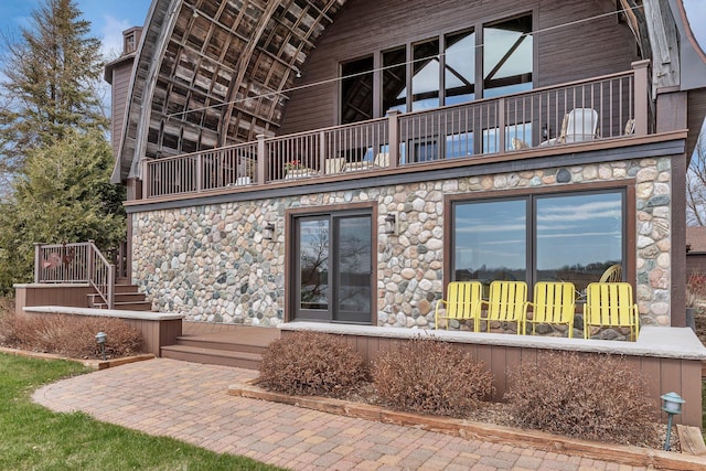 back of house with stone siding, stairway, and a balcony