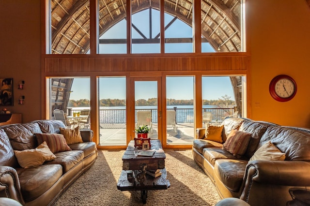 living area featuring a wealth of natural light, high vaulted ceiling, and a water view