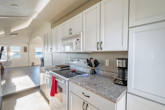 884 White Clover Beach Rd, Detroit Lakes, MN 56501 - kitchen with arched walkways, white cabinetry, vaulted ceiling, and white appliances