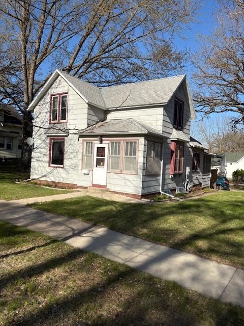 view of front of property with roof with shingles and a front lawn