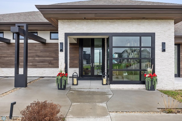 505 Tessa Dr, Moorhead, MN 56560 - view of exterior entry with stone siding, roof with shingles, and french doors