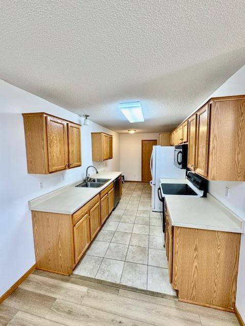 kitchen featuring a sink, dishwasher, black microwave, a textured ceiling, and electric stove