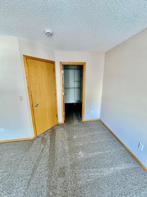 unfurnished bedroom with a closet, carpet flooring, baseboards, and a textured ceiling
