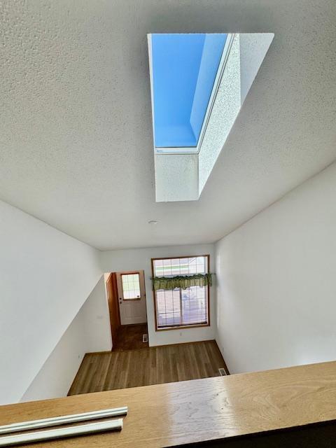 entryway featuring a skylight, wood finished floors, and a textured ceiling