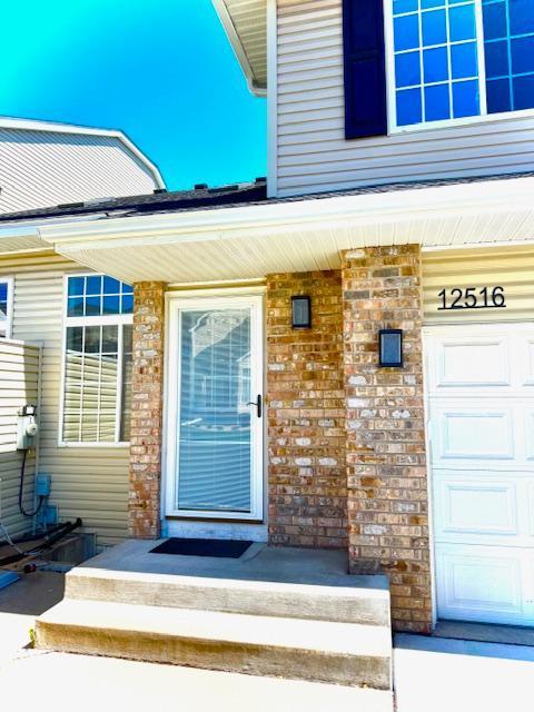 property entrance featuring a garage and brick siding