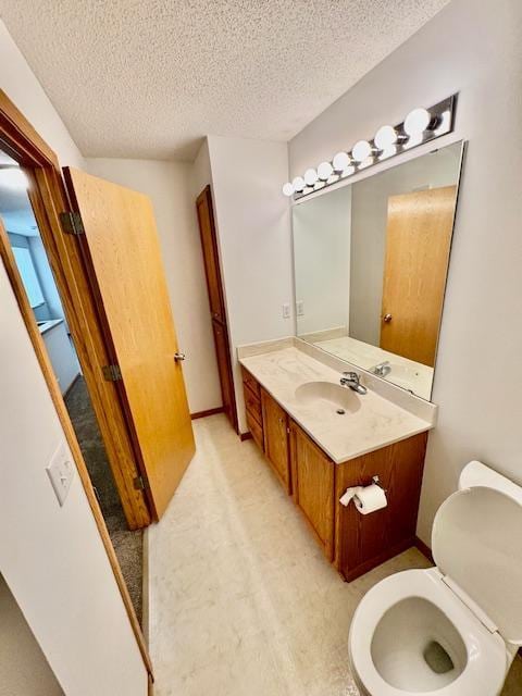 bathroom with a textured ceiling, vanity, toilet, and baseboards