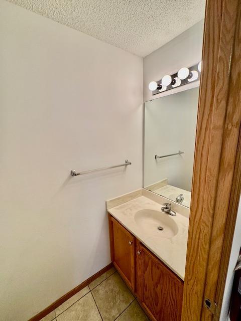 bathroom featuring a textured ceiling, tile patterned flooring, vanity, and baseboards