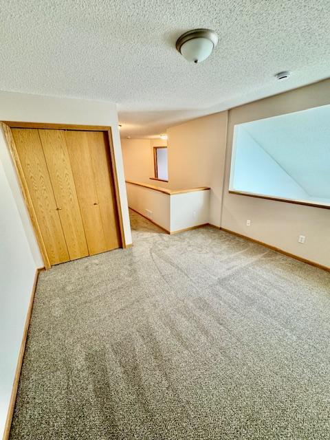 unfurnished bedroom featuring a closet, baseboards, a textured ceiling, and carpet