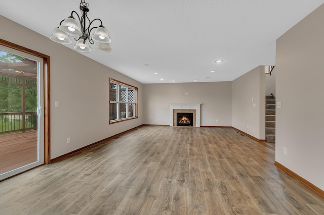 103 Grandview Ct, Buffalo, MN 55313 - unfurnished living room with light wood-type flooring, baseboards, a chandelier, a warm lit fireplace, and recessed lighting