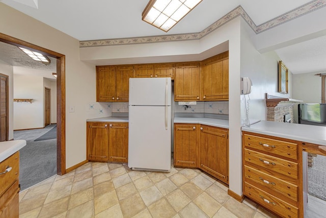 kitchen with freestanding refrigerator, light countertops, brown cabinetry, and open floor plan