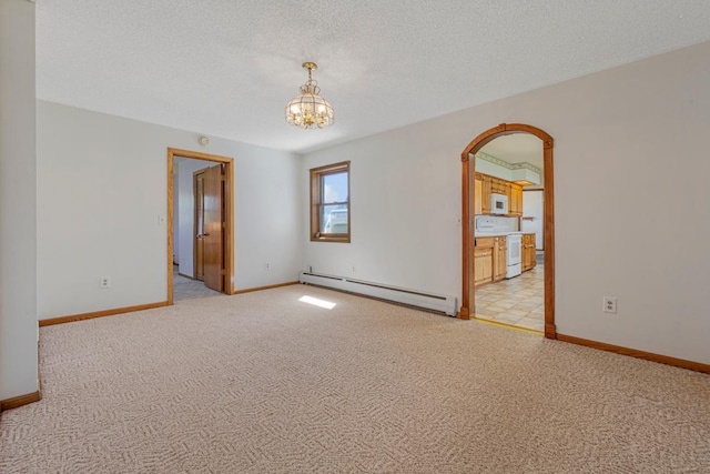 empty room with a baseboard heating unit, baseboards, an inviting chandelier, and light colored carpet