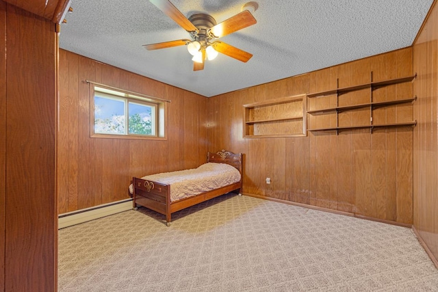bedroom with a textured ceiling, wood walls, a baseboard heating unit, and carpet floors