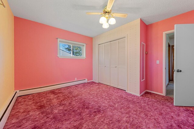 unfurnished bedroom with a textured ceiling, carpet, a closet, and a baseboard heating unit