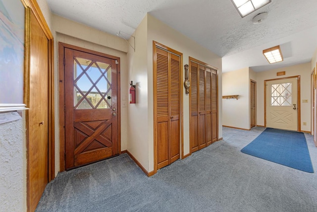 entryway featuring a textured ceiling, baseboards, and carpet floors