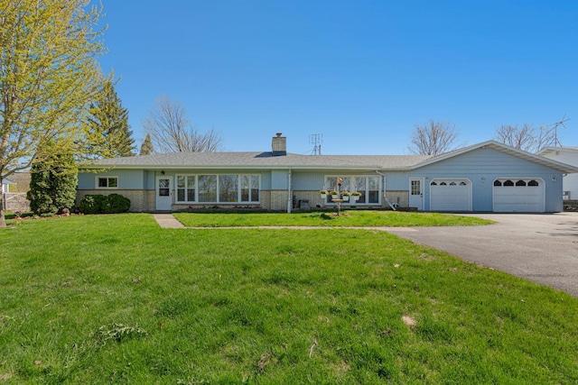 ranch-style house featuring a garage, a chimney, aphalt driveway, a front lawn, and brick siding