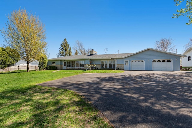 ranch-style house with an attached garage, fence, a chimney, a front yard, and driveway