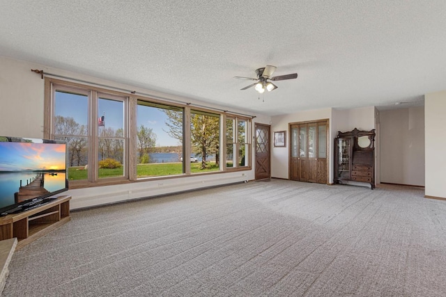 unfurnished living room featuring ceiling fan, a textured ceiling, carpet flooring, and baseboards
