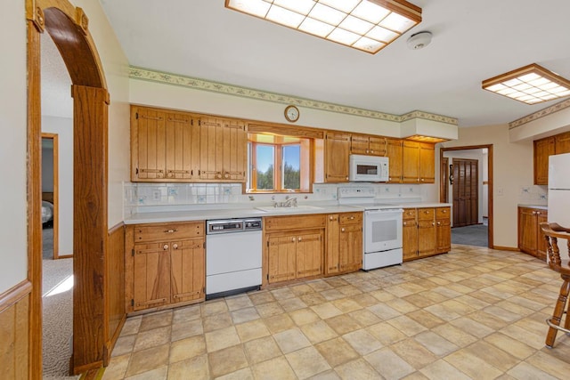 kitchen featuring white appliances, a sink, decorative backsplash, and light countertops