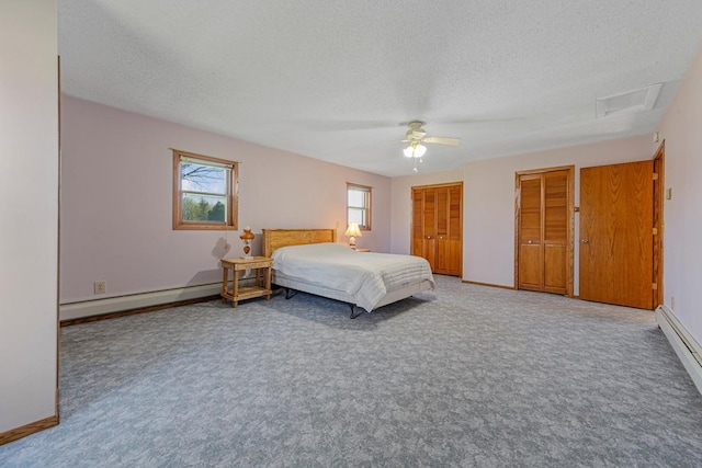 carpeted bedroom featuring a baseboard radiator, a textured ceiling, multiple windows, two closets, and attic access