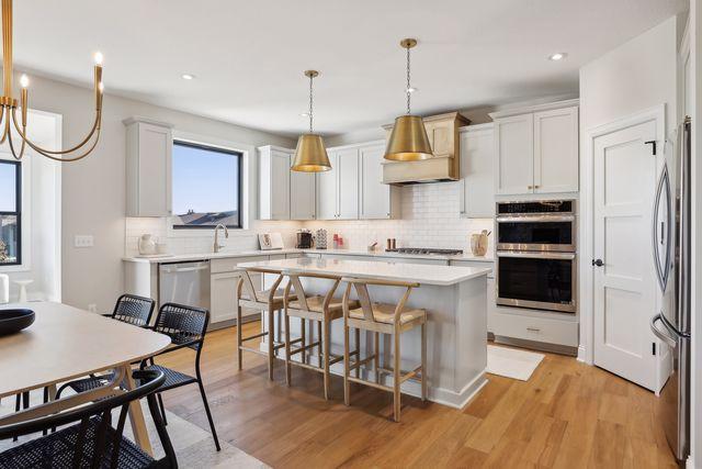4029 Arbor Dr, Woodbury, MN 55129 - kitchen featuring stainless steel appliances, decorative backsplash, a kitchen island, light wood-style floors, and light countertops