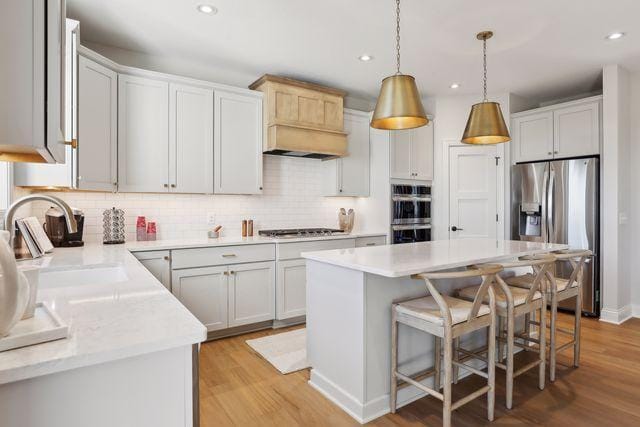4029 Arbor Dr, Woodbury, MN 55129 - kitchen featuring appliances with stainless steel finishes, a sink, light wood-style flooring, backsplash, and recessed lighting