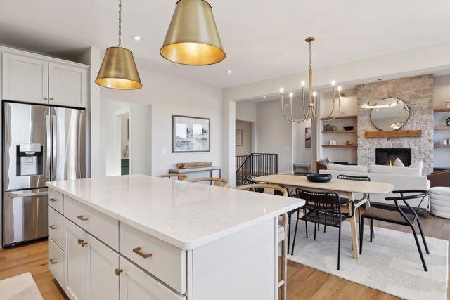 4029 Arbor Dr, Woodbury, MN 55129 - kitchen with stainless steel fridge, light wood-style flooring, white cabinetry, open floor plan, and recessed lighting