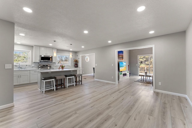 13804 Euclid Ct, Apple Valley, MN 55124 - kitchen with stainless steel appliances, recessed lighting, a kitchen island with sink, light countertops, and a textured ceiling