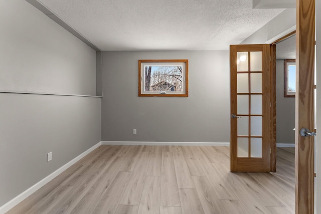 13804 Euclid Ct, Apple Valley, MN 55124 - spare room featuring a textured ceiling, french doors, light wood-style floors, and baseboards