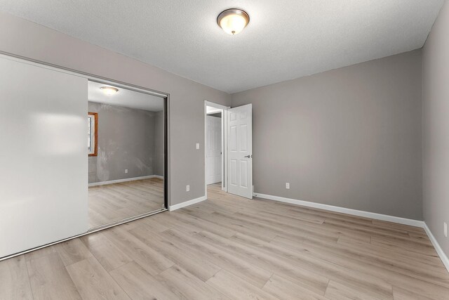 13804 Euclid Ct, Apple Valley, MN 55124 - unfurnished bedroom featuring light wood-style flooring, a textured ceiling, and a closet