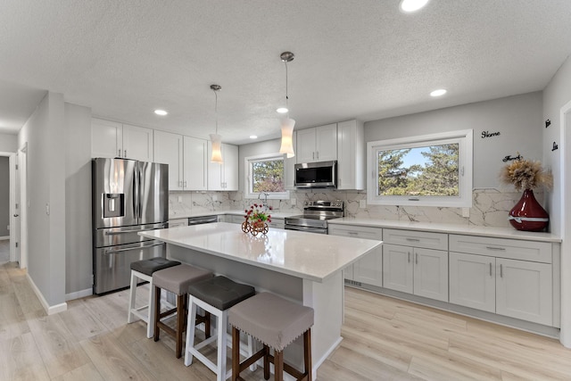 13804 Euclid Ct, Apple Valley, MN 55124 - kitchen with stainless steel appliances, a textured ceiling, light wood-style flooring, a kitchen bar, and recessed lighting