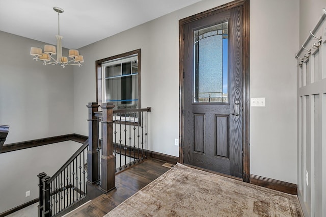entrance foyer featuring baseboards, a notable chandelier, and dark wood-type flooring
