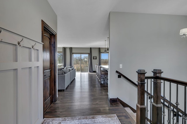 hallway featuring an upstairs landing and dark wood-type flooring