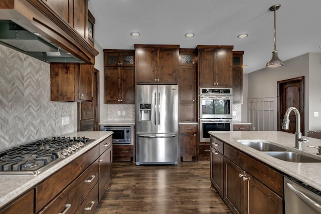 kitchen with decorative light fixtures, a sink, dark wood-style floors, under cabinet range hood, and stainless steel appliances