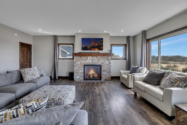 living area featuring recessed lighting, baseboards, a stone fireplace, and dark wood-type flooring