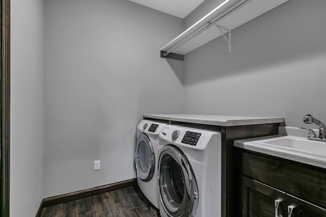washroom with baseboards, dark wood finished floors, washer and clothes dryer, a sink, and cabinet space