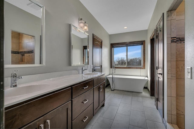 bathroom featuring double vanity, a freestanding bath, a sink, and tile patterned flooring