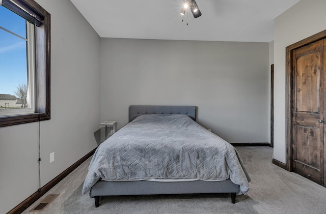bedroom featuring baseboards, ceiling fan, light carpet, and visible vents