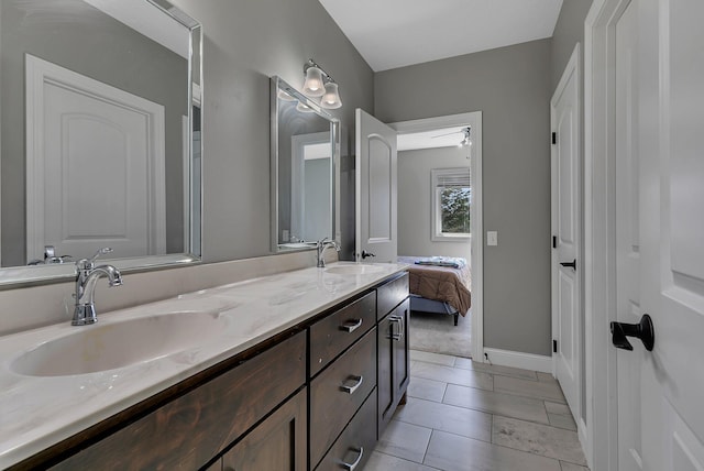 bathroom featuring double vanity, baseboards, and a sink