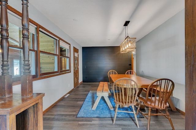 dining space featuring baseboards, wood finished floors, and wooden walls