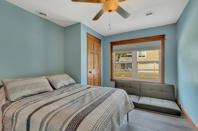 bedroom with ceiling fan, baseboards, wood finished floors, and visible vents