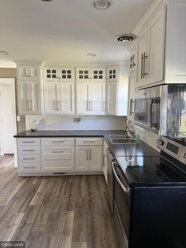kitchen with white cabinets, stainless steel appliances, a sink, visible vents, and backsplash