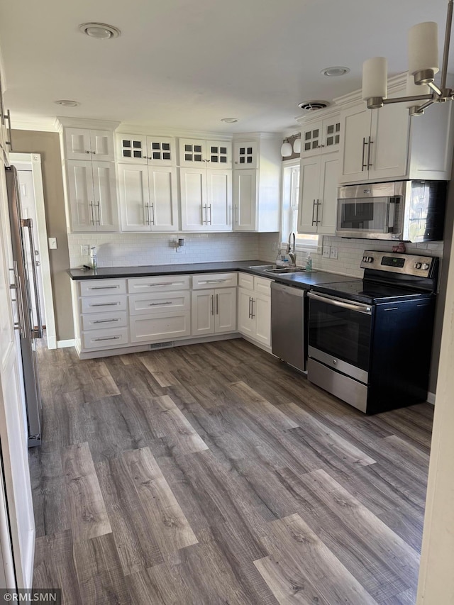 kitchen with dark countertops, visible vents, tasteful backsplash, appliances with stainless steel finishes, and white cabinetry