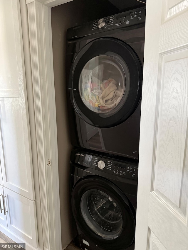 clothes washing area with stacked washing maching and dryer and laundry area