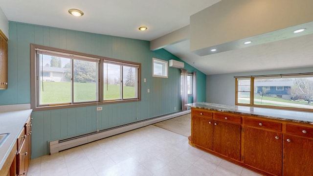 kitchen with a baseboard heating unit, vaulted ceiling, light countertops, brown cabinetry, and a wall mounted air conditioner