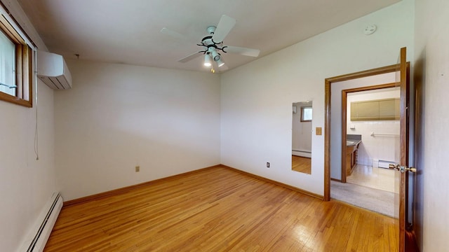 empty room with a baseboard heating unit, an AC wall unit, light wood-type flooring, and a smoke detector