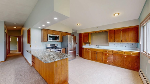 kitchen with stainless steel appliances, a baseboard radiator, brown cabinetry, a sink, and a peninsula