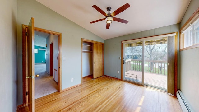 unfurnished bedroom featuring baseboard heating, access to outside, lofted ceiling, light wood finished floors, and a closet