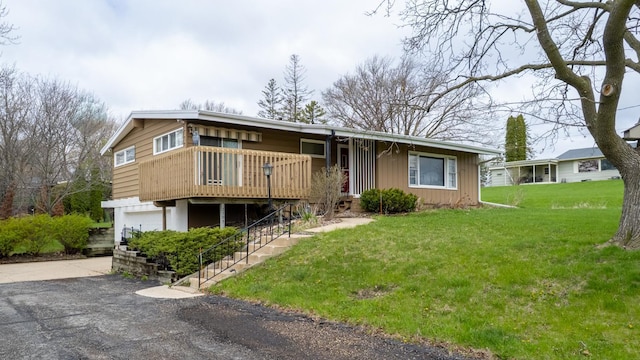 view of front of property with asphalt driveway, a front yard, an attached garage, and stairway